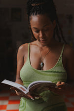 Load image into Gallery viewer, Model wearing a spaghetti strap green dress reads book with a serpentine gemstone necklace on
